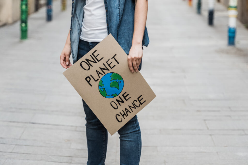 Bild på en person som håller i en skylt där det står "One planet, one chance".