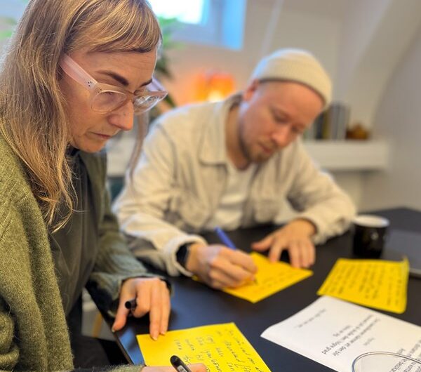 En kvinna och en man skriver på stora gula postit-lappar.