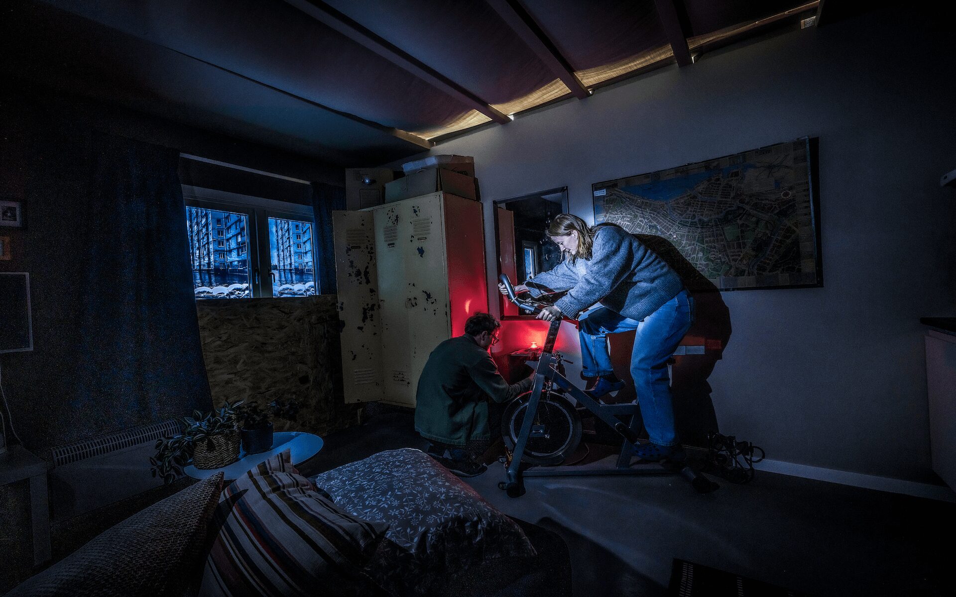 En person cyklar på en cykel som genererar elektricitet i en mörk lägenhet.