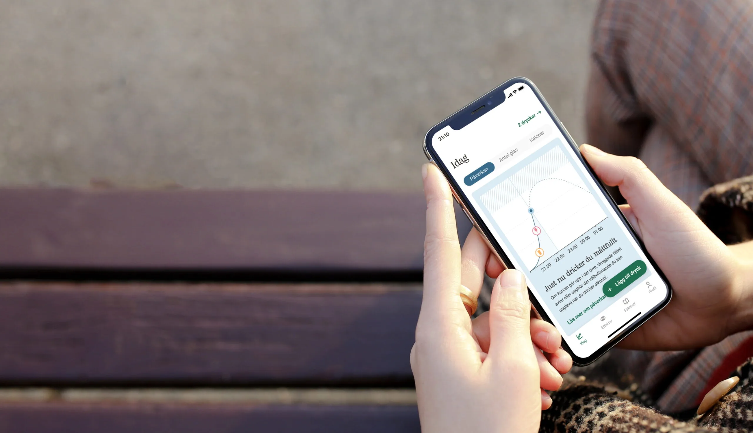 En hand håller i en mobil med Systembolagets app öppen