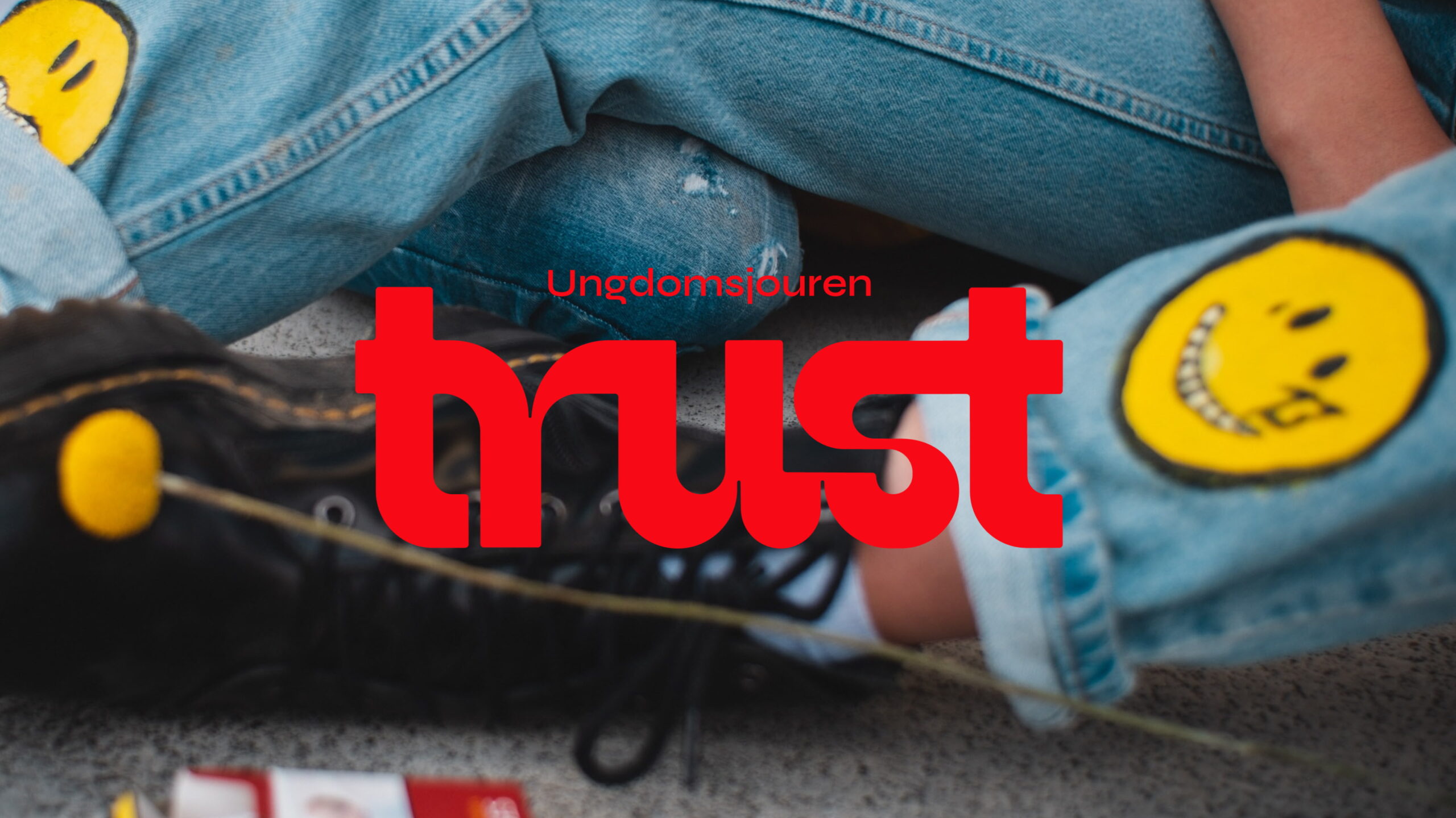 En bild av ett par jeans och en text där det står "ungdomsjouren trust", logotyp designad av Antrop